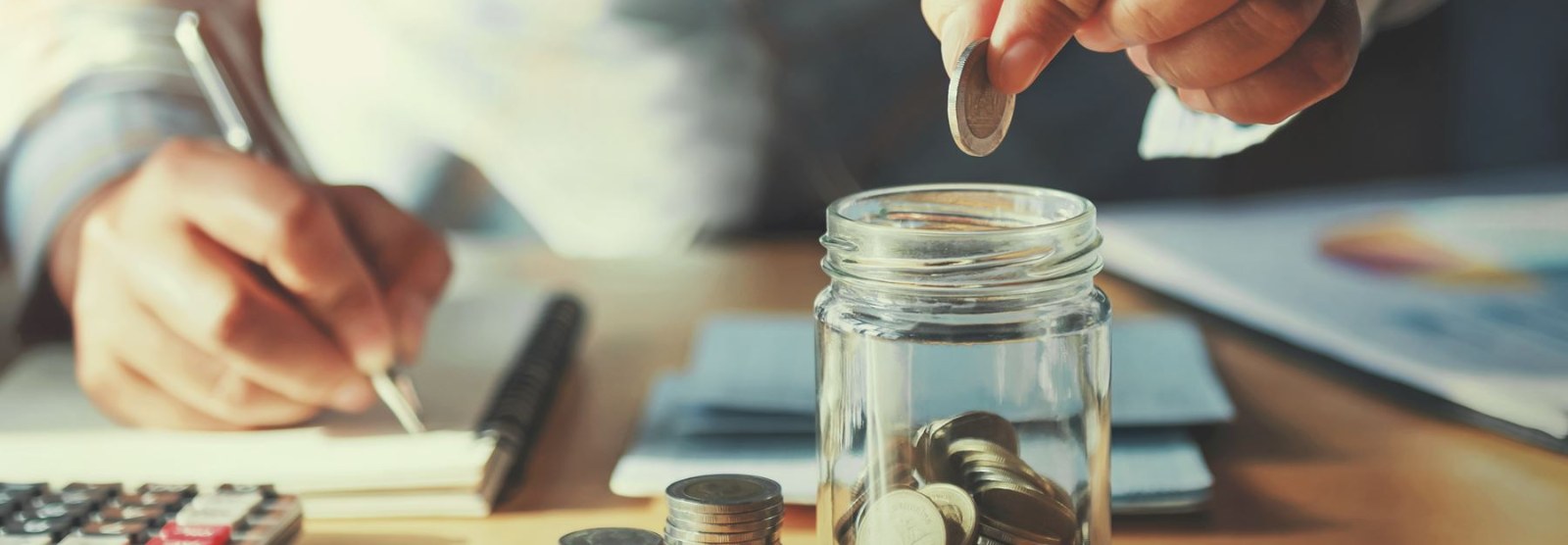 a person putting coins in a glass jar